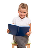 little girl sitting on a chair with blue book and smiling