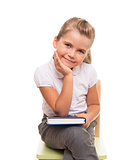 little girl sitting on a chait with book on the knee