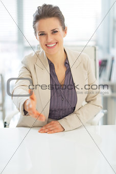 Smiling business woman stretching hand for handshake