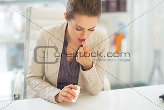 Business woman taking pill at work