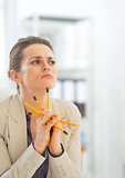 Portrait of thoughtful business woman holding pencils