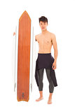 young surfer wearing diving suit and holding a surfboard