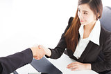 smiling business woman shaking hands with client in her office