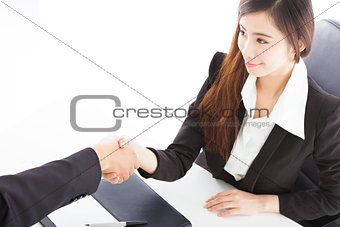 smiling business woman shaking hands with client in her office