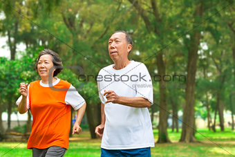 happy senior couple running together in the park