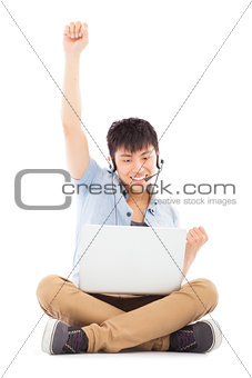 successful Young man sitting on floor and using a laptop