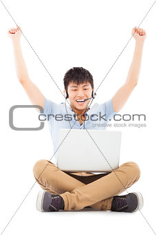 successful Young man sitting on floor and raising hands