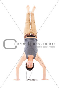 young man doing a handstand against and listening music