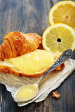 Lemon curd and teaspoon on a slice of fresh croissant.  