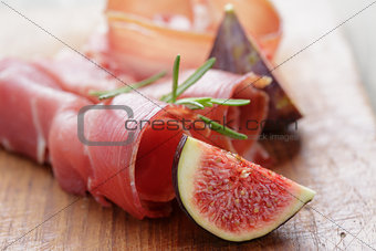 dried jamon slices with figs on wood table