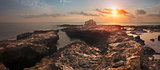 Sunset over the Sea and Rocky Coast with Ancient Ruins