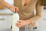 Closeup on young woman opening milk