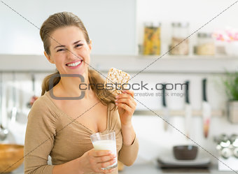 Happy young woman having snacks in kitchen