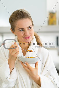 Portrait of young woman eating muesli in kitchen