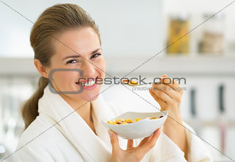 Happy young woman eating muesli in kitchen
