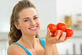 Portrait of happy young woman showing tomato
