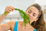 Portrait of young woman smelling fresh dill