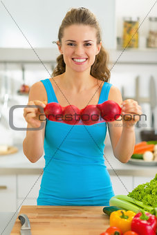 Happy young woman showing onion in kitchen