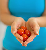 Closeup on young woman showing cherry tomato