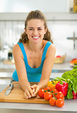 Portrait of young woman with fresh vegetables in kitchen