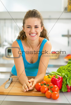 Portrait of young woman with fresh vegetables in kitchen