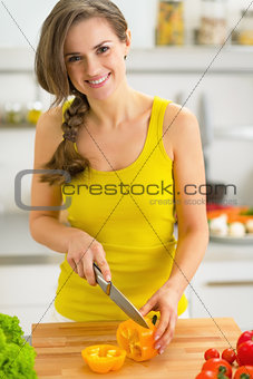 Happy young woman cutting bell pepper