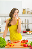 Happy young woman in kitchen licking fingers