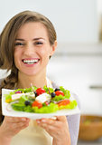 Portrait of happy young housewife showing fresh salad