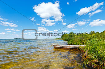 Summer lake view with wooden boat.