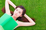 smiling girl student  laying down  on a meadow with books