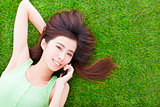 pretty girl lying down on a meadow  and talking by smartphone