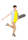 Vibrant young man holding a skateboard and walking 