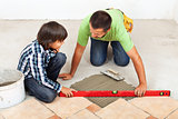Man and boy laying ceramic floor tiles together