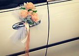Door of white wedding car with flowers and white bow