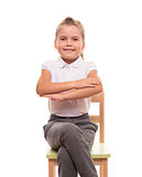 little schoolgirl sitting on a chair and holding her hands in fr