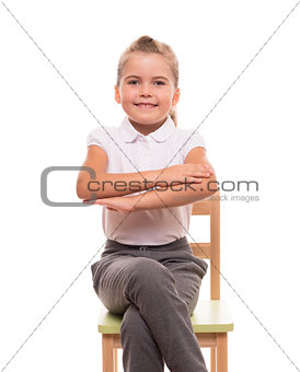 little schoolgirl sitting on a chair and holding her hands in fr