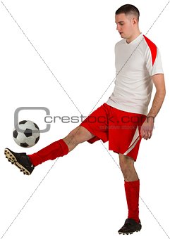 Fit football player playing with ball