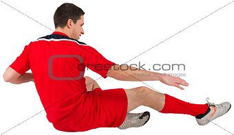 Fit football player jumping and kicking
