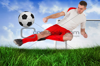 Fit football player playing and kicking ball
