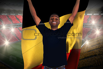 Excited football fan in black cheering holding belgium flag