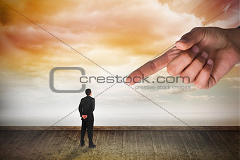 Giant hand pointing at businessman standing and looking