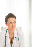Medical doctor woman sitting in office and looking on copy space