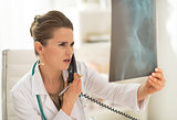 Medical doctor woman looking on fluorography and talking phone