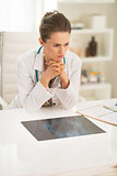 Thoughtful medical doctor woman with fluorography in office