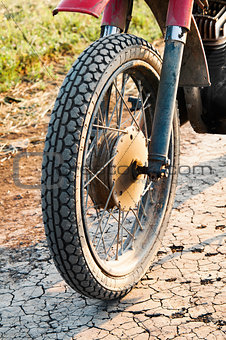 Old wheel motorcycle on a dirt road.