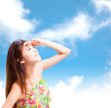 young woman raising hand to cover sunlight with blue sky