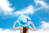 back of  girl holding a hat with blue sky background