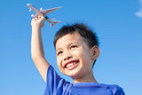 happy boy playing a airplane toy with blue sky background