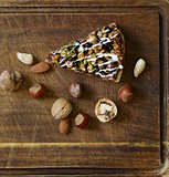 piece of pecan pie tart with various nuts on a wooden board
