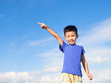 happy little boy pointing direction with blue sky background